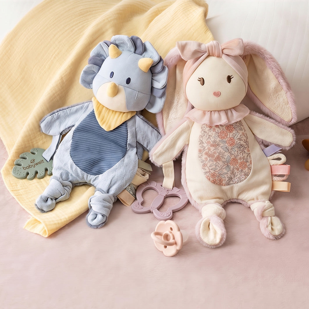 Doudou Dino accanto al Doudou Coniglietto sul letto